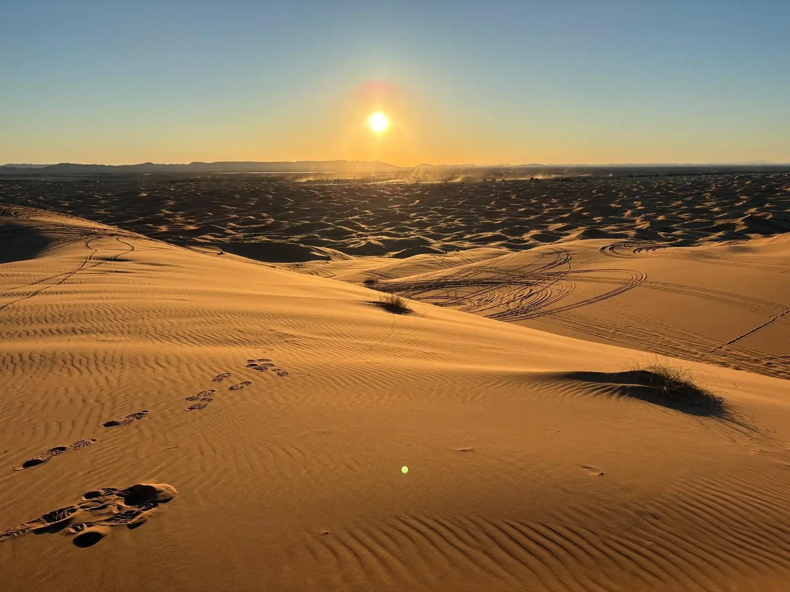 Dunas del desierto al atardecer, con huellas sobre la arena