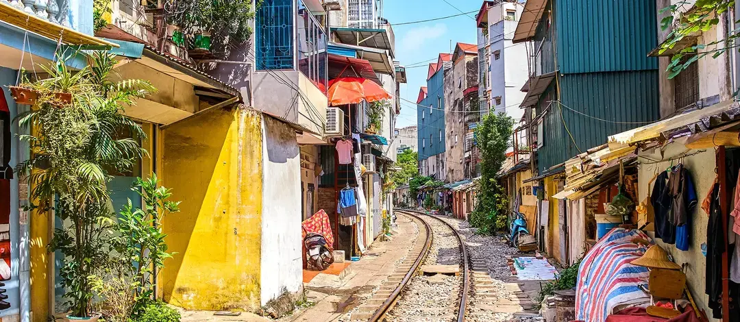 Calle del tren de Hanói, con las vías entre casas de colores, plantas y puestos