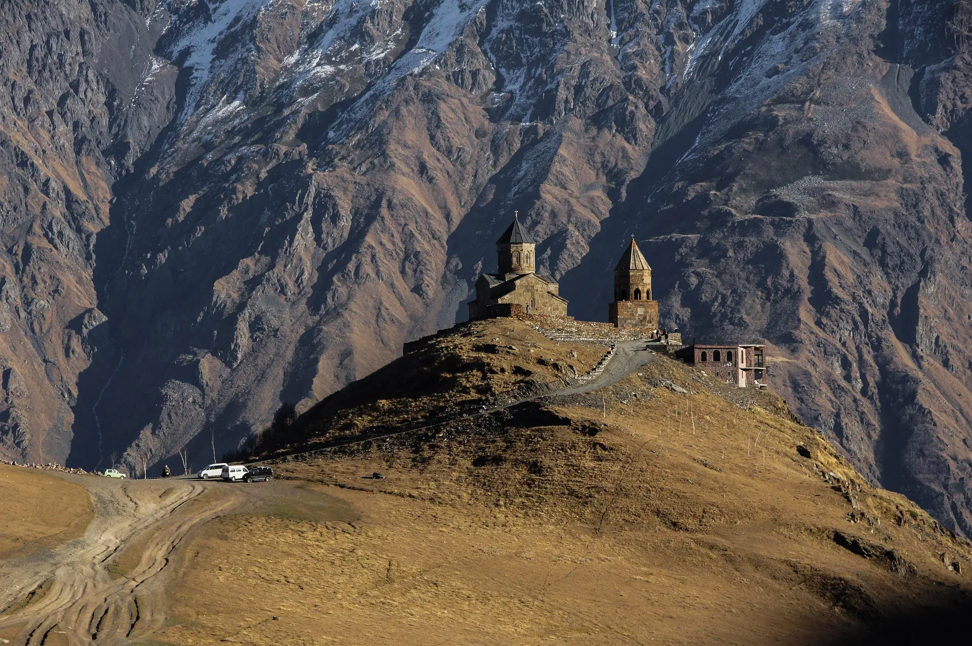 Iglesia de la Trinidad de Gergeti sobre una colina, frente a las laderas del Cáucaso en Kazbegi, Georgia