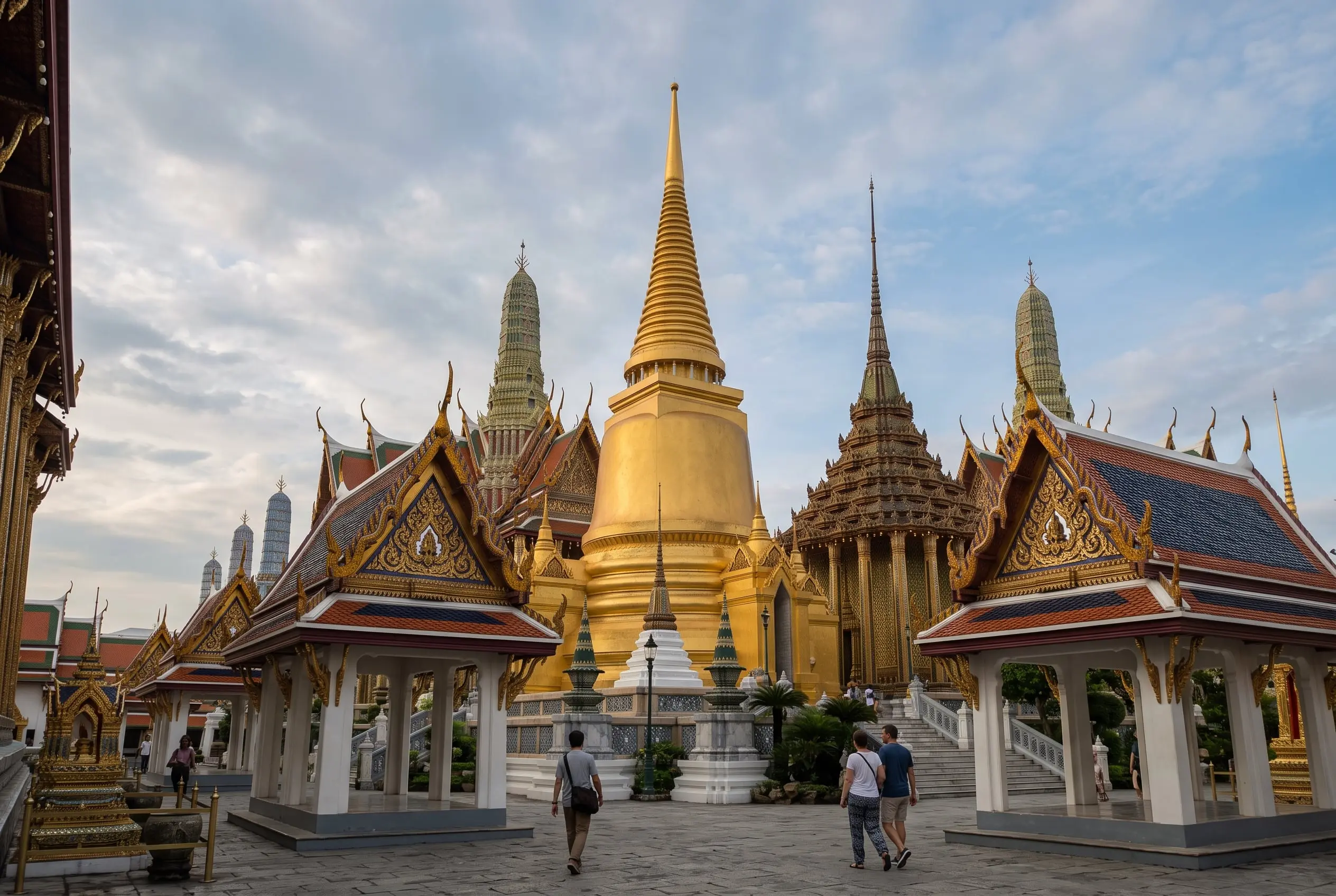 Estupa dorada y pabellones de tejados escalonados del recinto del Gran Palacio de Bangkok, con visitantes paseando
